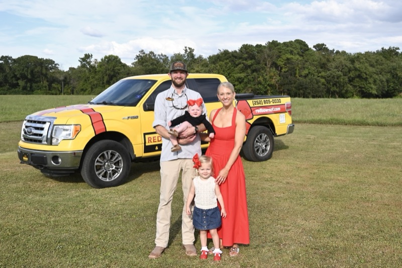 Ryan Chatt with his wife and two daughters in front of the Red Bow Roofing truck